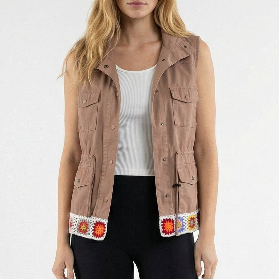 Woman wearing a beige vest, white top, black leggings, and beige shoes on a white background